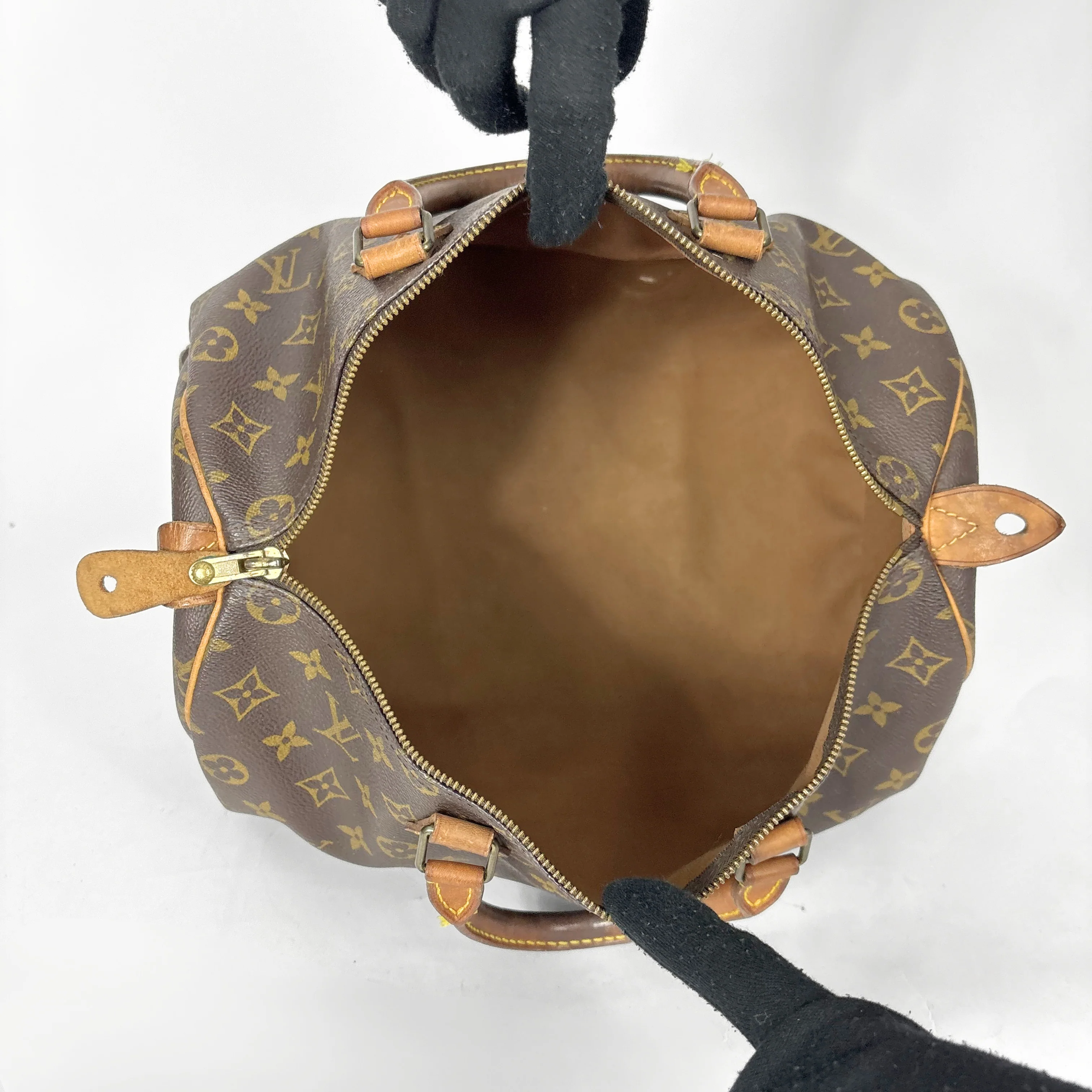 Brown leather bag with gold monogram pattern on a white background