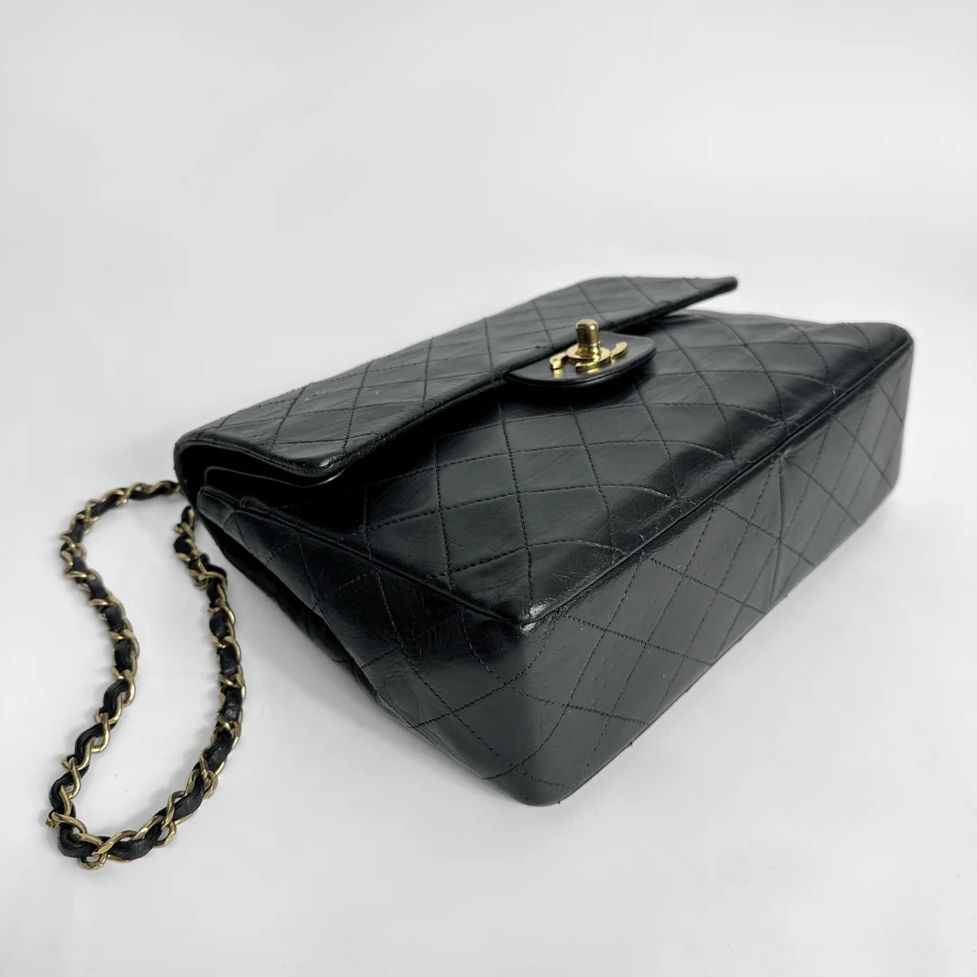 Black quilted handbag with a chain strap on a white background