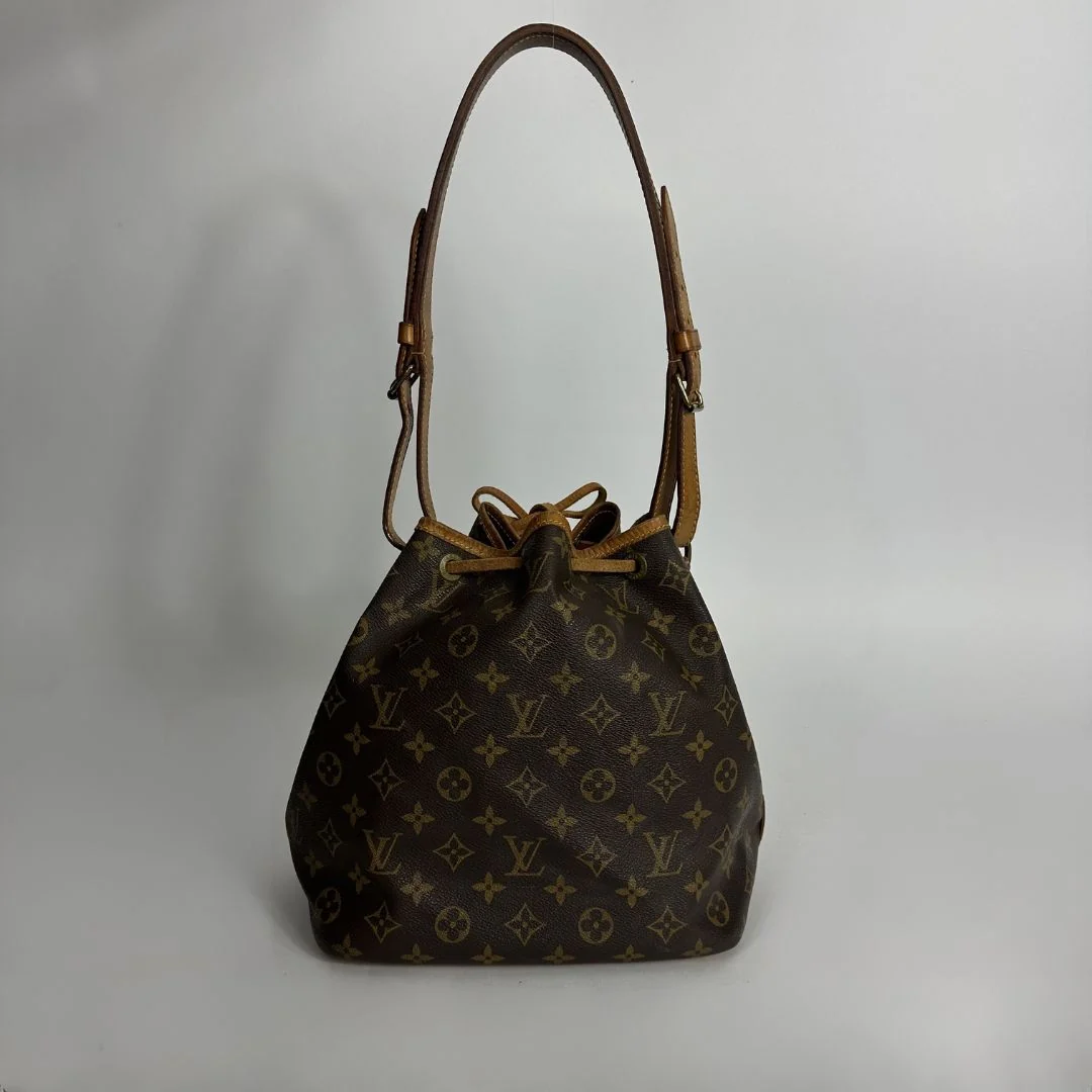 Louis Vuitton monogram canvas shoulder bag with a brown leather strap and drawstring closure, photographed against a neutral light gray background.