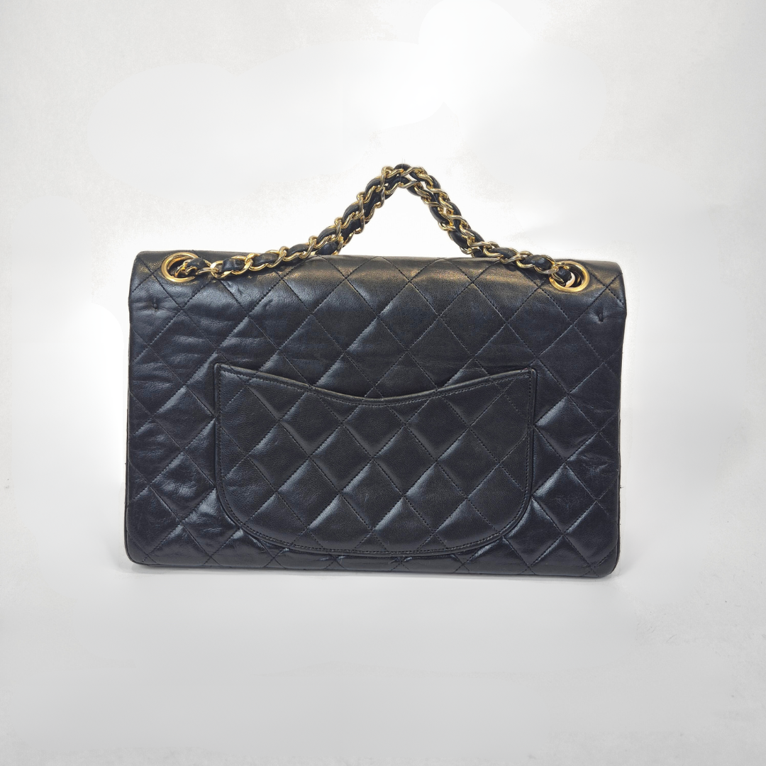 Black Chanel handbag with gold chain handle and clasp on a white background