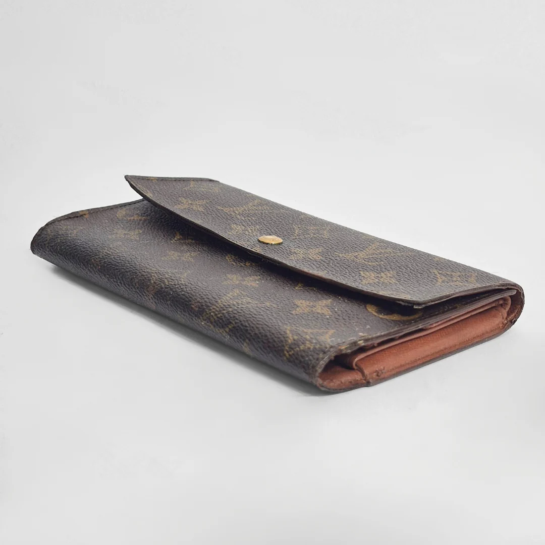 Vintage-style wallet with monogram pattern on a light gray background