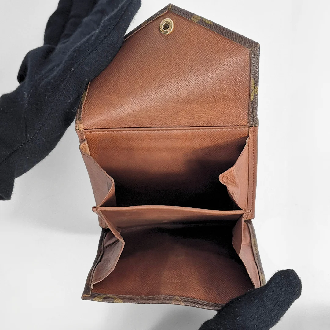 Brown leather wallet with a black glove holding it open on a white background