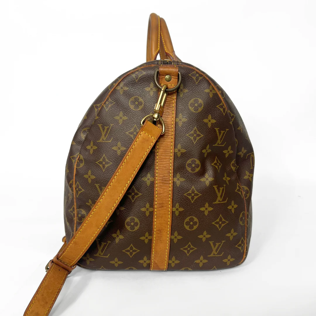 Brown leather handbag with gold monogram pattern on a white background