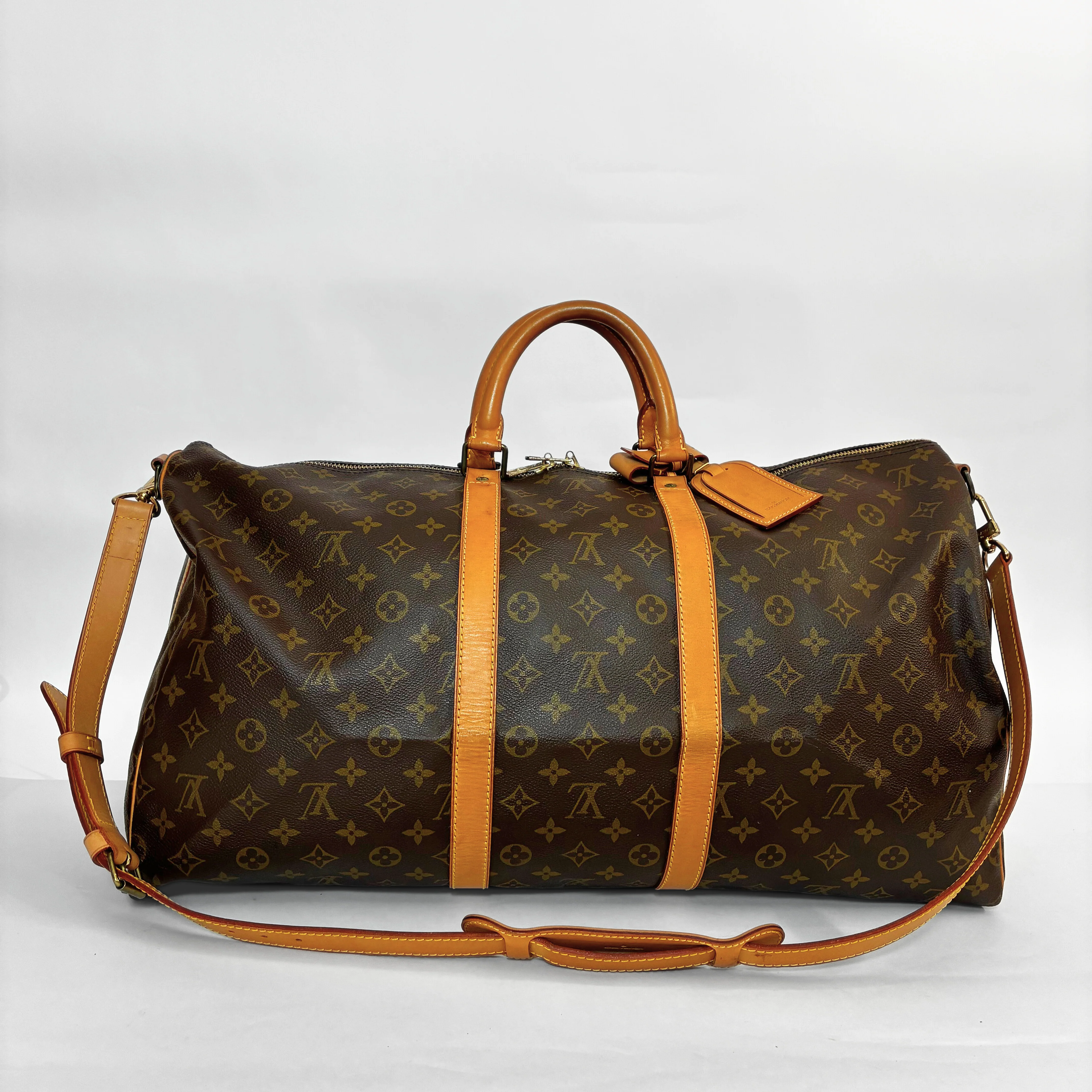 Louis Vuitton monogram travel bag with brown leather straps on a white background