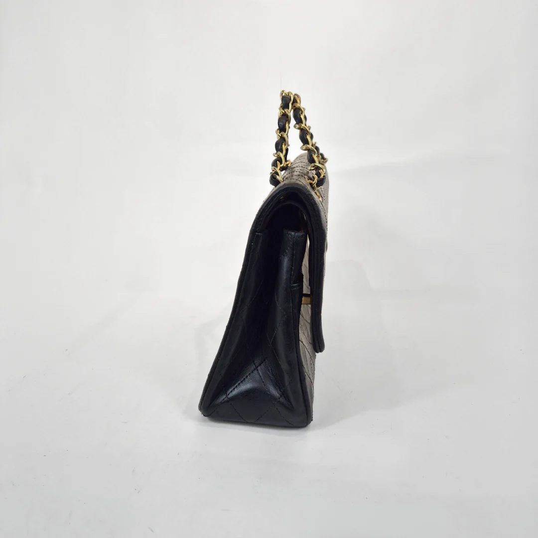 Black handbag with gold chain strap on a white background