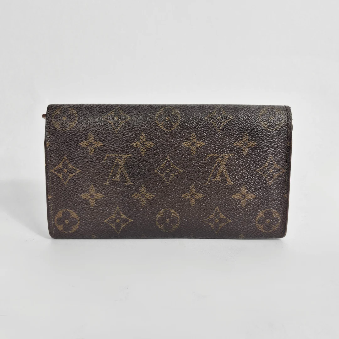 Designer wallet with monogram pattern on a light gray background