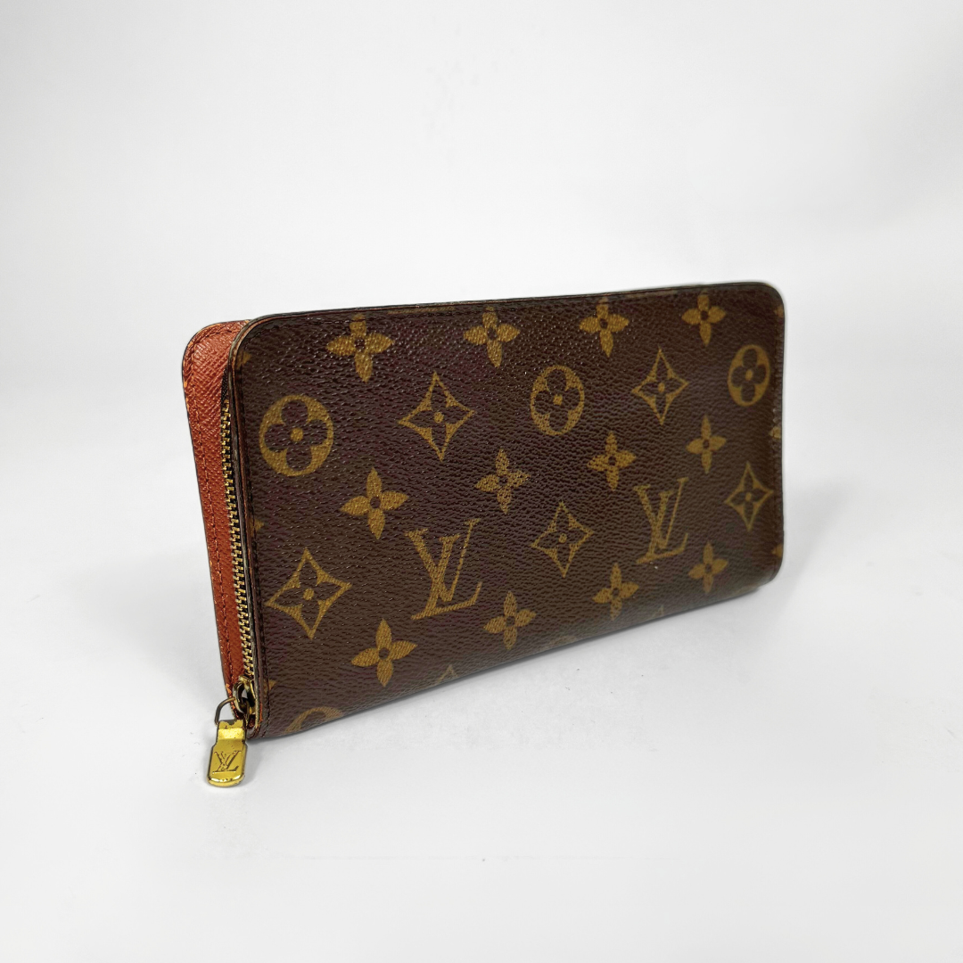 Brown wallet with gold monogram pattern on a white background