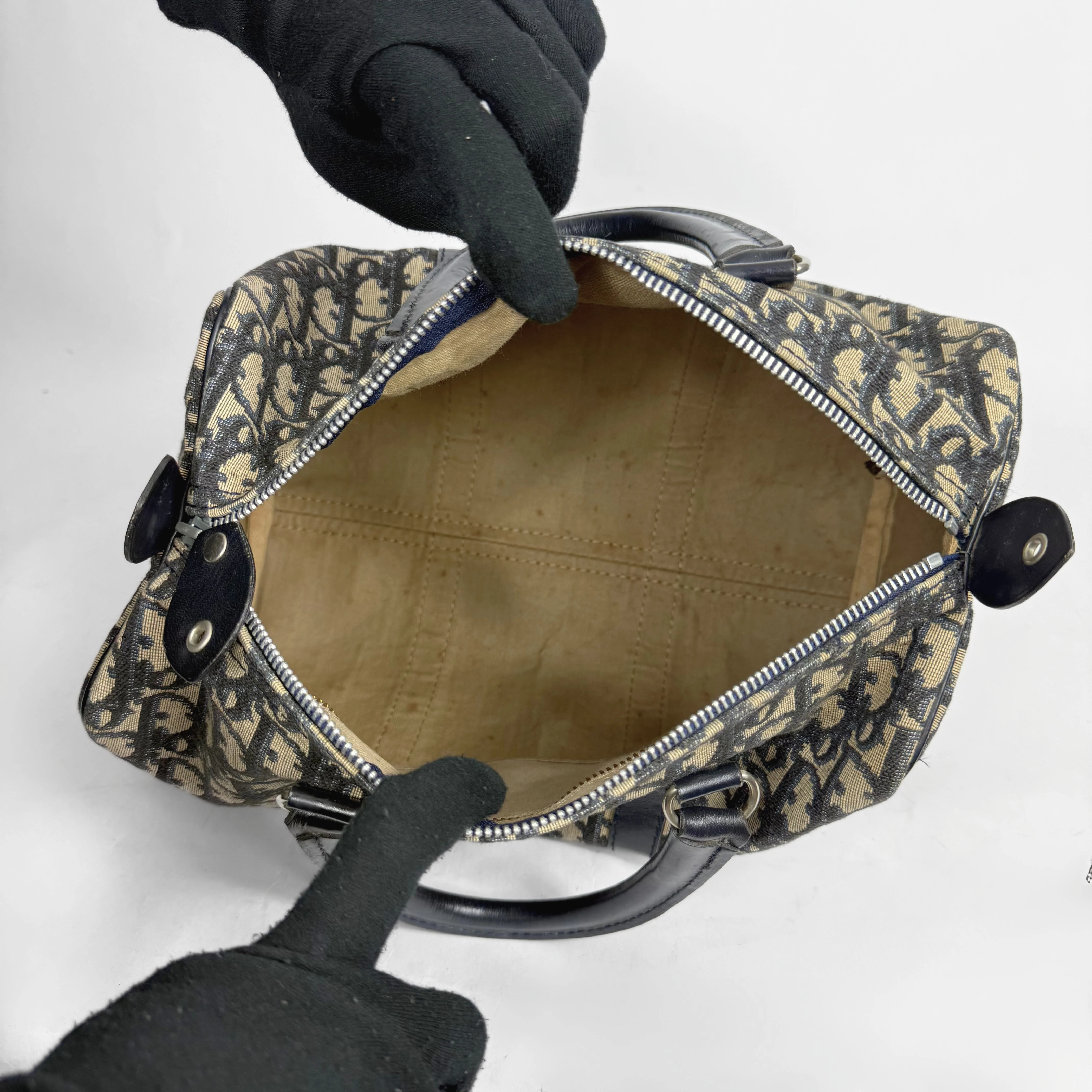 Handbag with floral pattern held open by a gloved hand on a white background