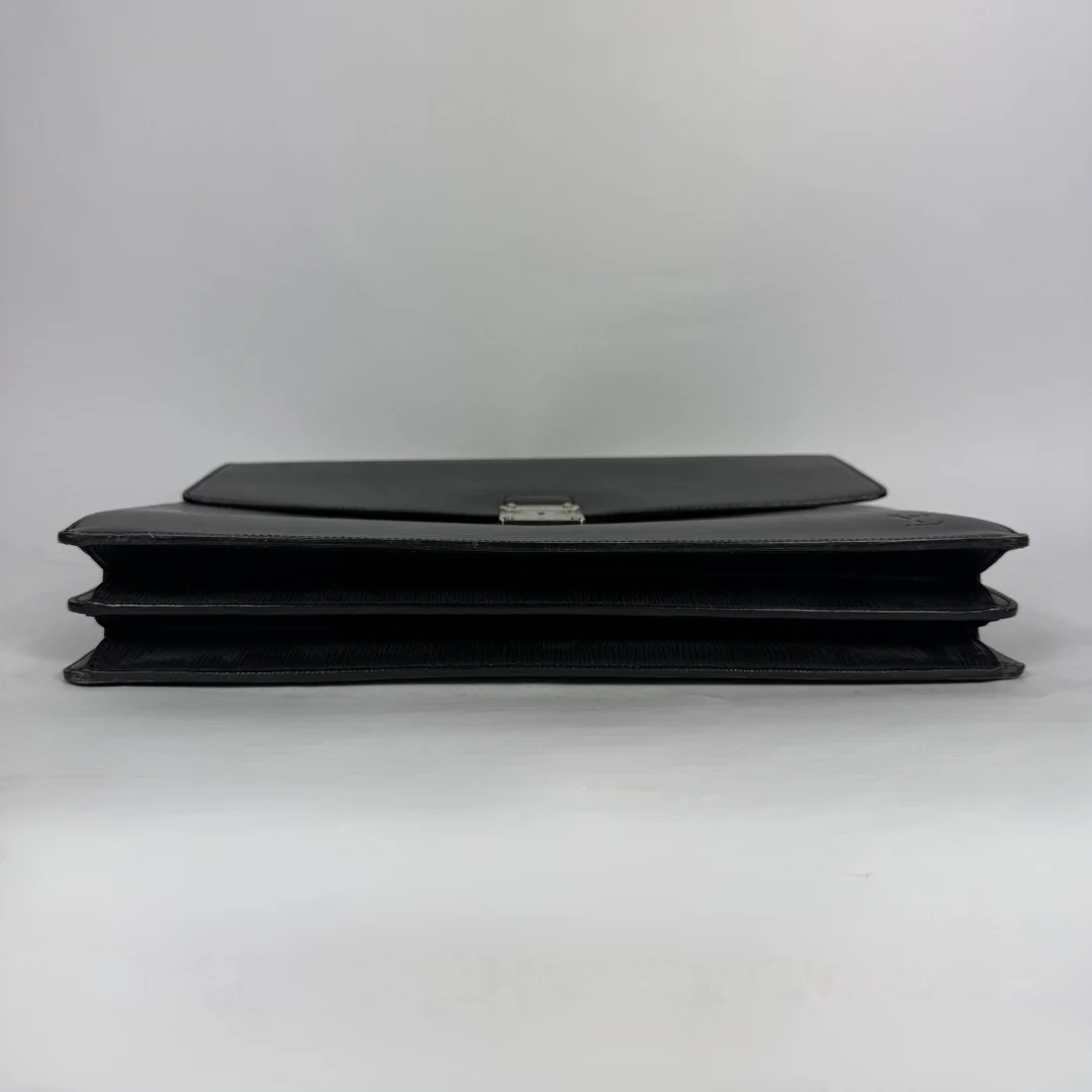 A black leather clutch bag with a silver-tone metal clasp, shown from the side on a light gray background.