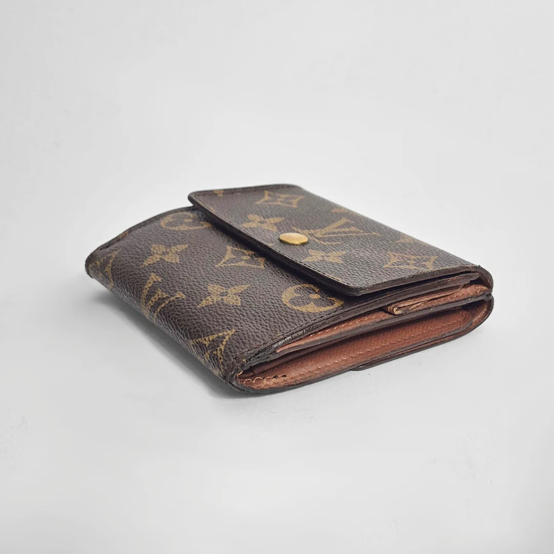Folded brown leather wallet with gold monogram pattern on a light gray background