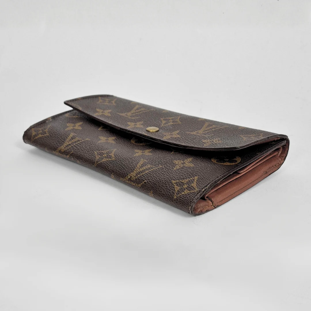 Designer wallet with monogram pattern on a light gray background