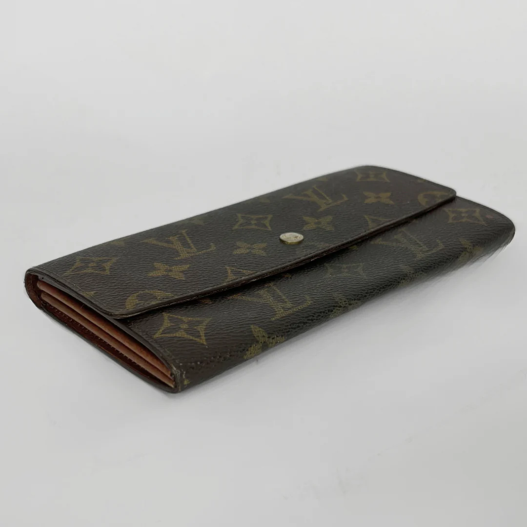 Brown wallet with gold monogram pattern on a light gray background