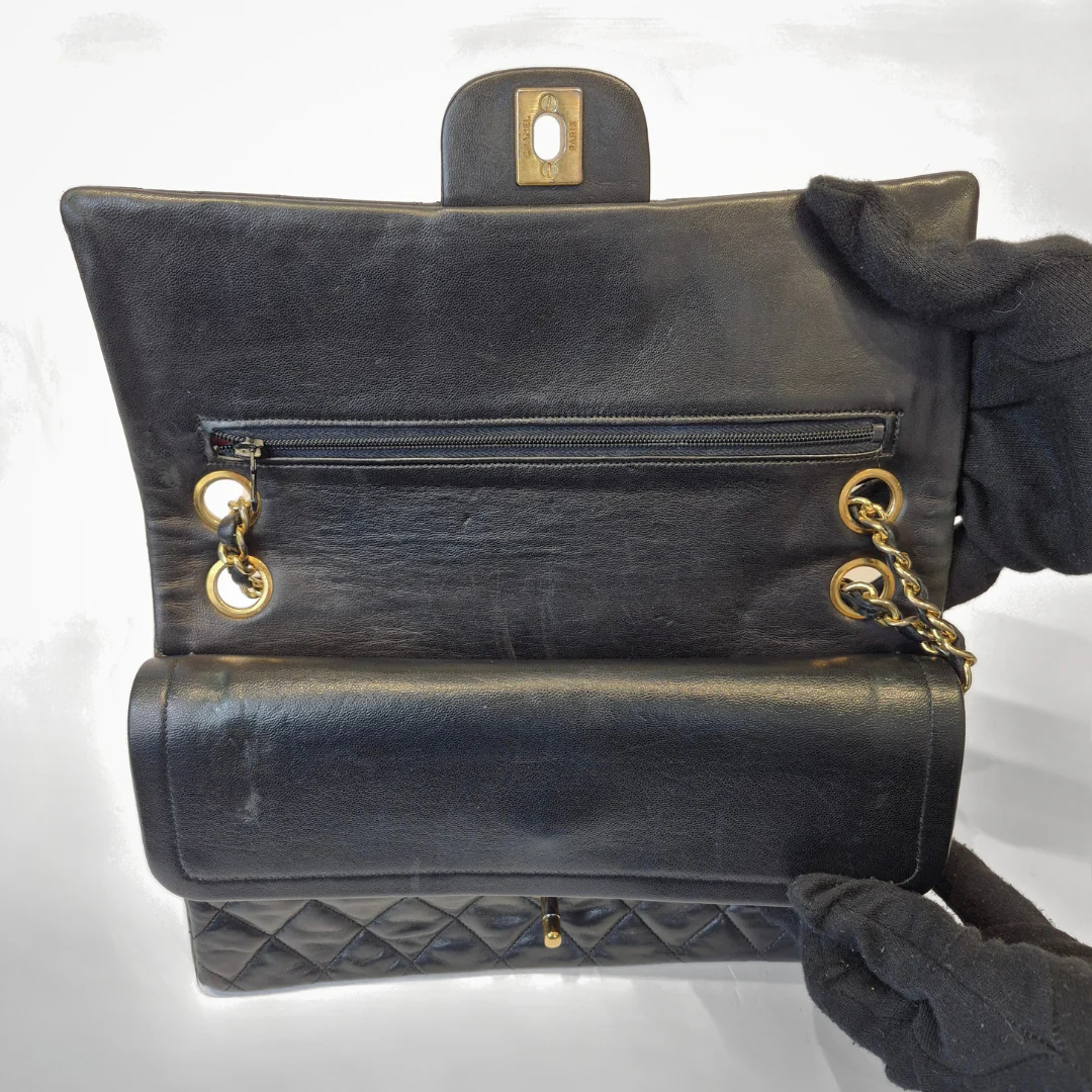 Black leather handbag with gold hardware on a white background