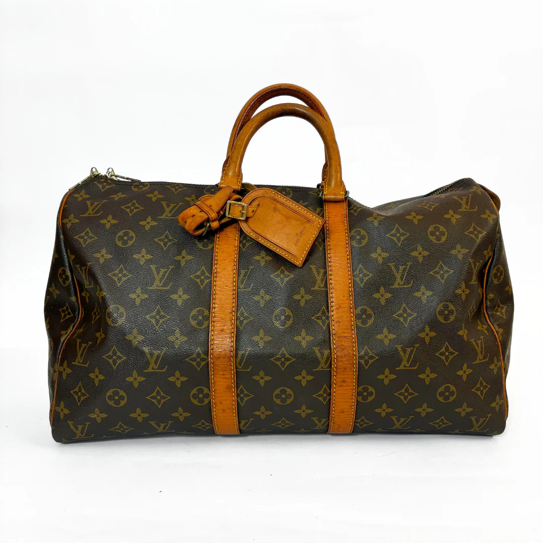 Louis Vuitton monogram handbag with brown leather straps on a white background