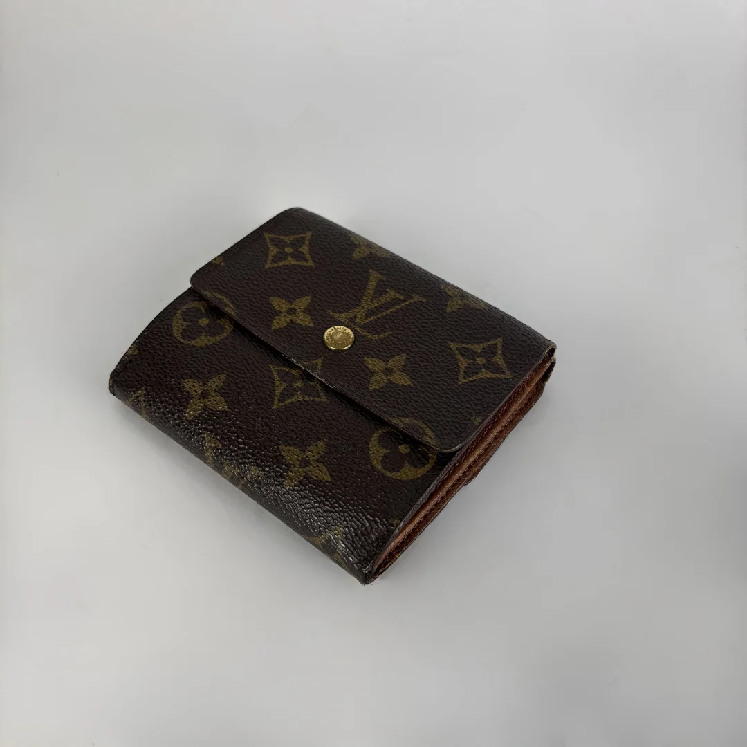 A Louis Vuitton monogram bifold wallet in dark brown coated canvas with gold-tone hardware, photographed on a light gray background.