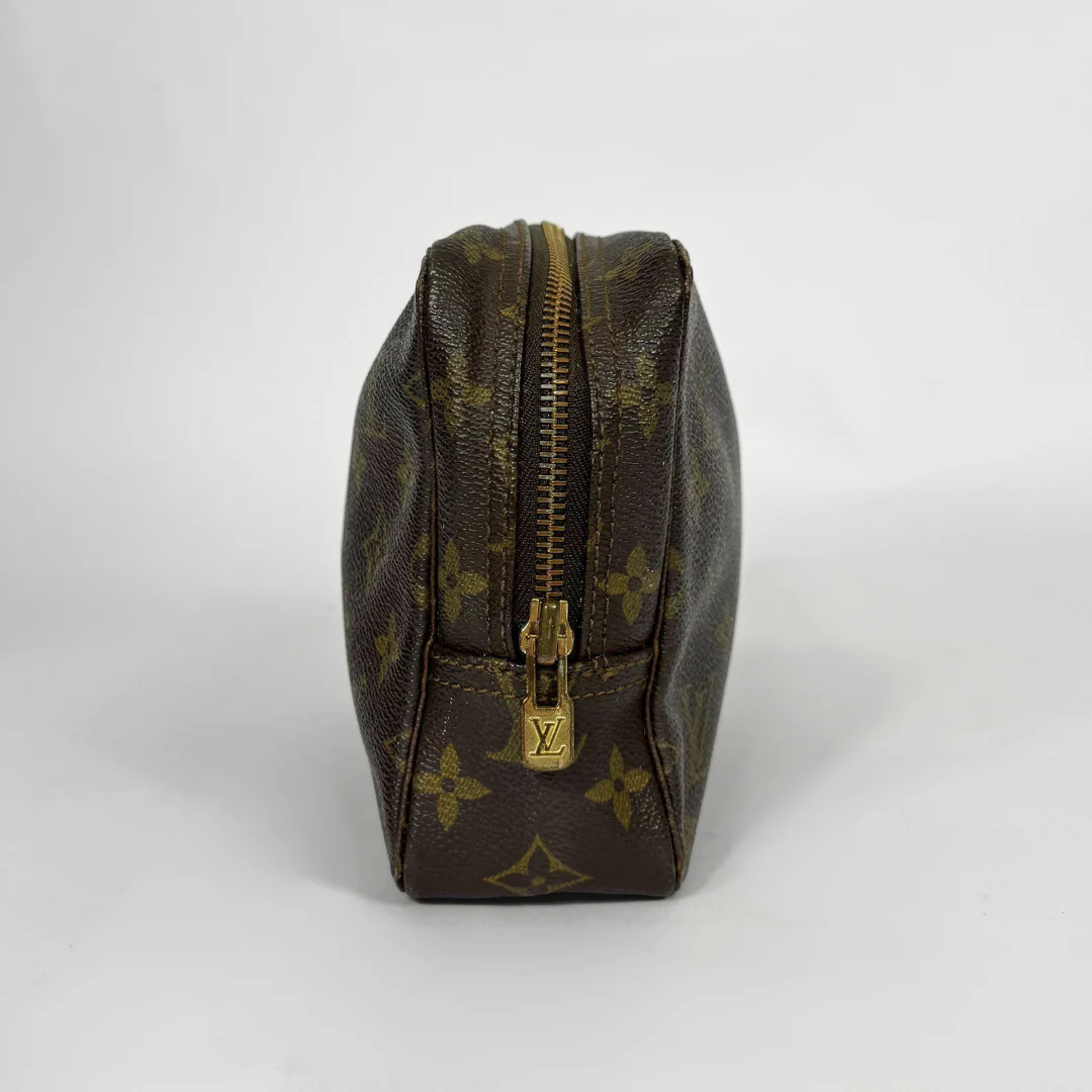 Brown leather toiletry bag with gold zipper and logo on a white background