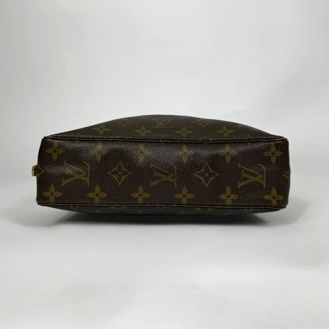 Brown leather handbag with monogram pattern on a white background