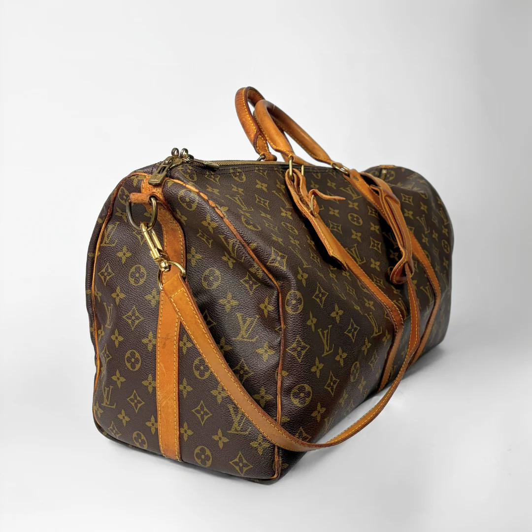 Brown leather duffel bag with tan accents on a white background