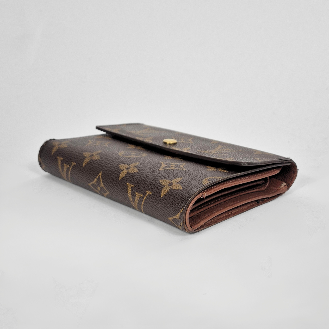 Brown wallet with gold monogram pattern on a light gray background