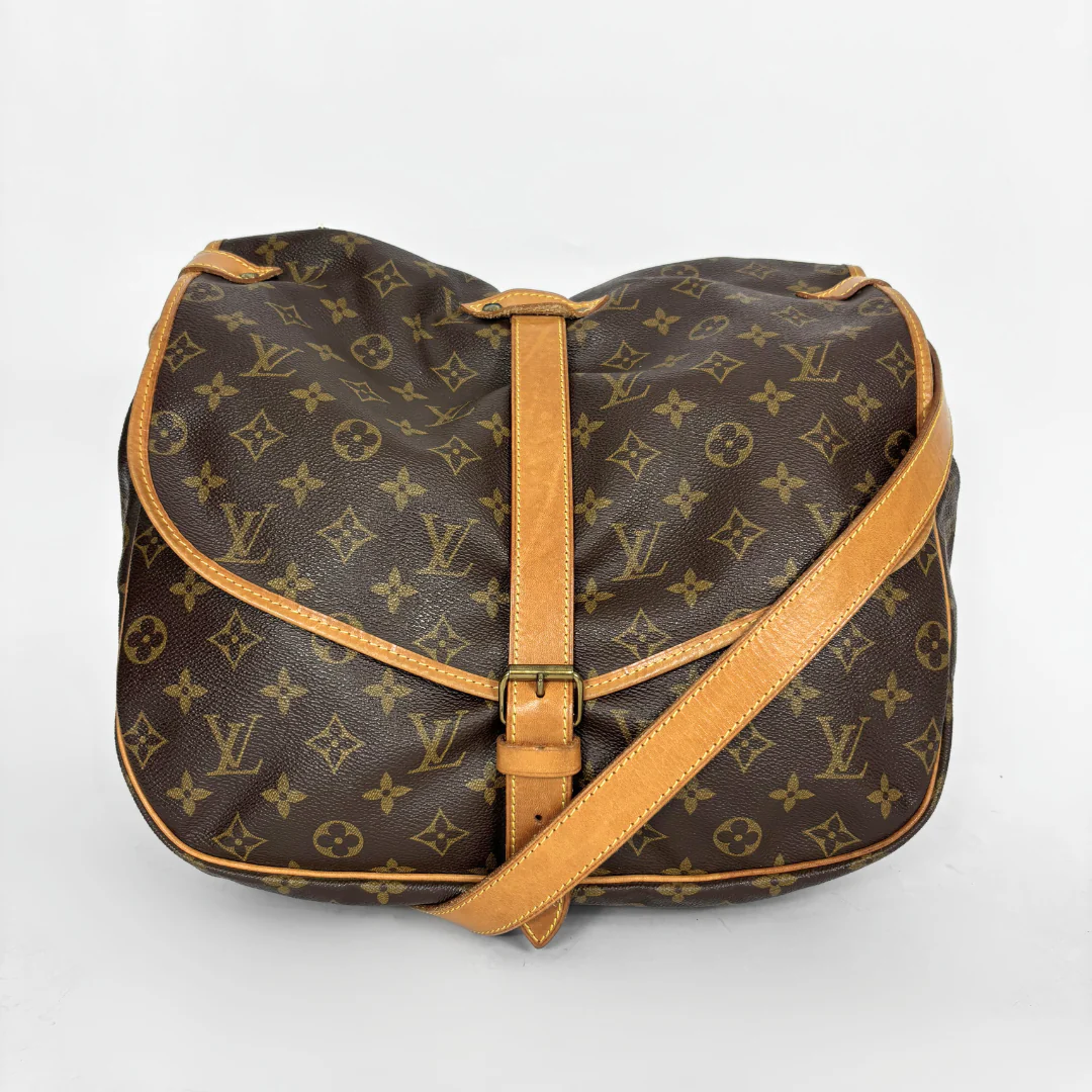 Brown monogram handbag with tan leather strap on a white background