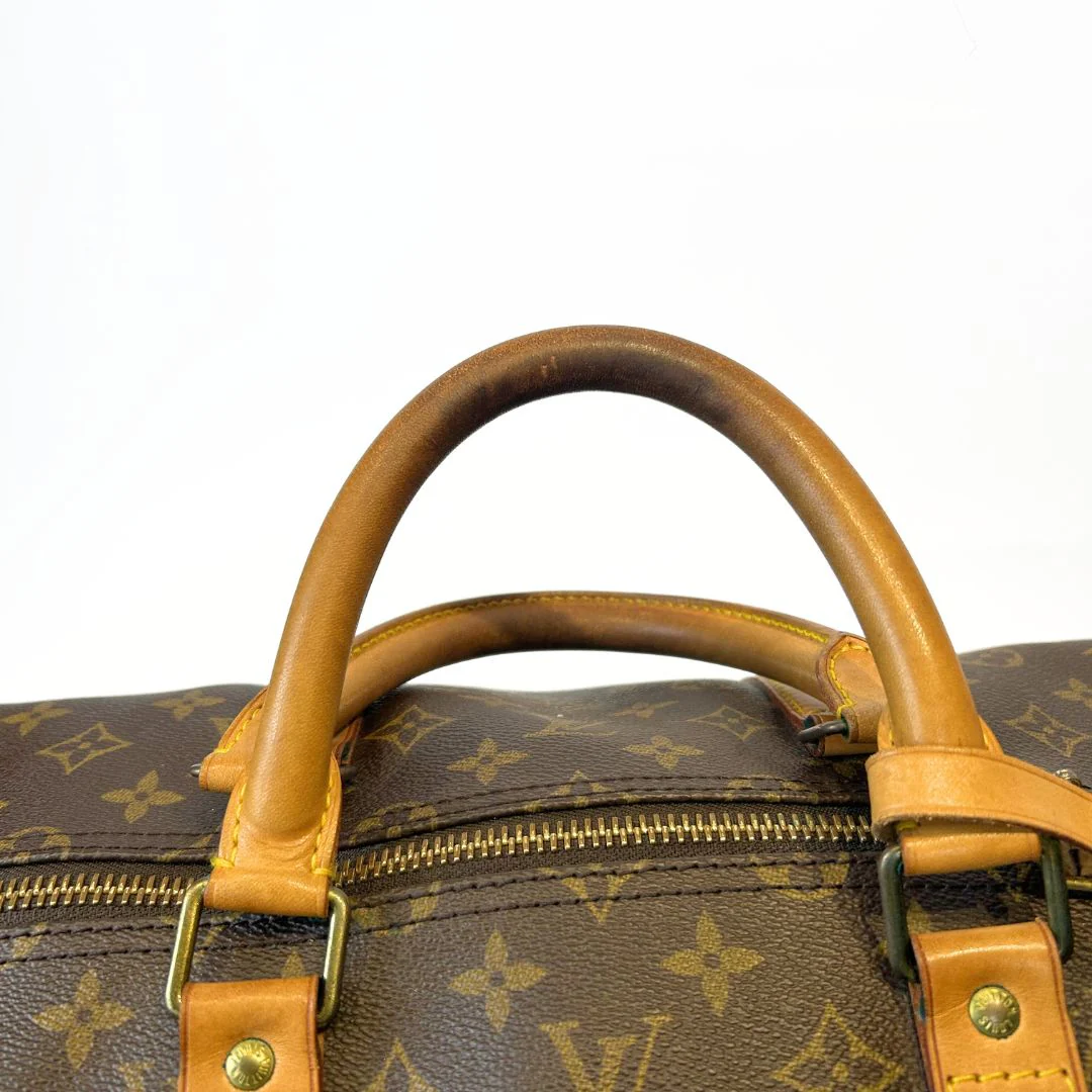Close-up of a brown leather handle on a Louis Vuitton monogram bag.