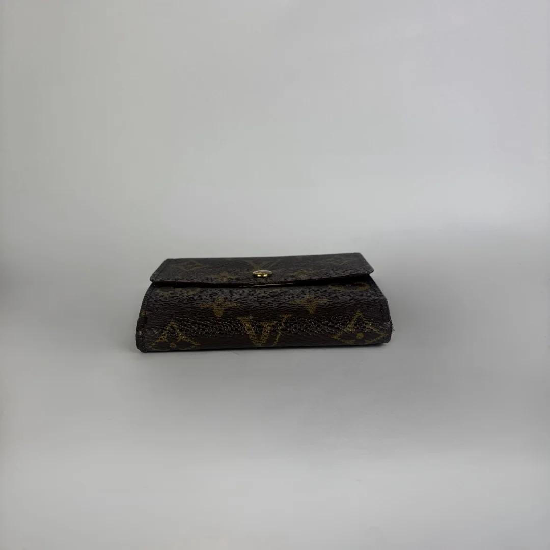 A dark brown Louis Vuitton monogram clutch wallet with a gold-tone snap button closure, set against a plain light gray background.